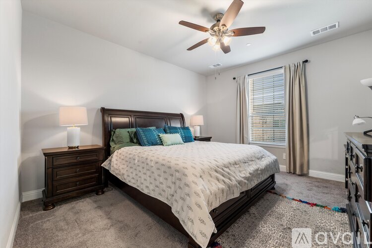 A bedroom with a large bed and a ceiling fan.