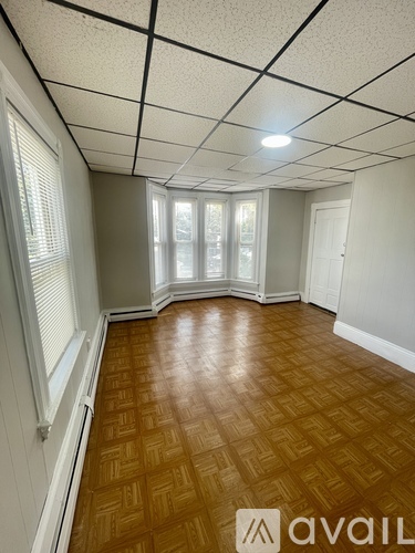 A room with wooden flooring and a window with blinds.