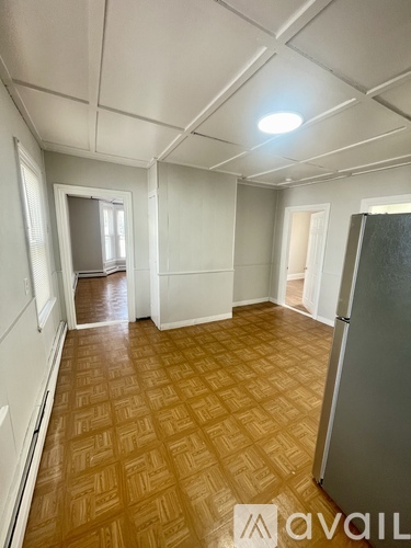 A room with a wooden floor and a refrigerator.