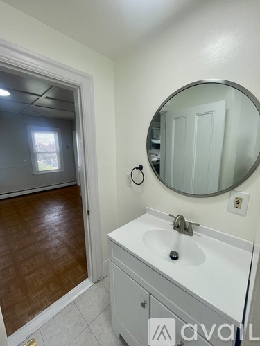 A bathroom with a sink, mirror, and wooden floor.