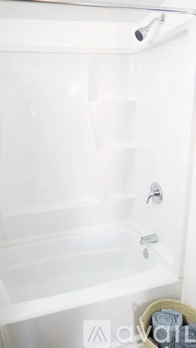 A white bathtub with a shower head and faucet.