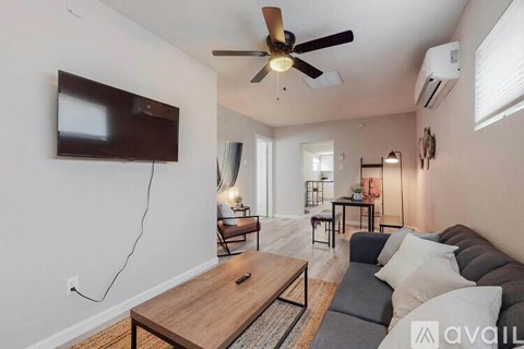 A living room with a flat screen TV mounted on the wall and a ceiling fan.