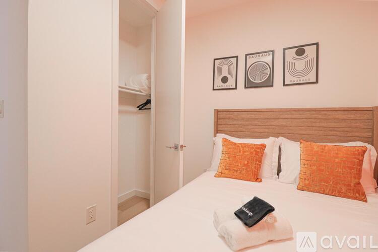 A bedroom with a bed, pillows, and pictures on the wall.