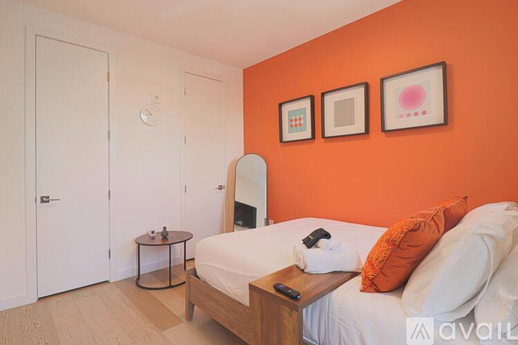 A bedroom with orange walls and a bed with white bedding.