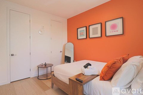A bedroom with orange walls and a bed with white bedding.