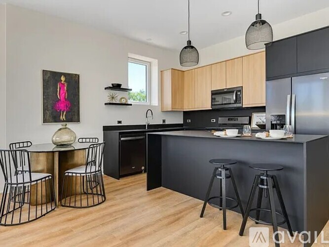 A kitchen with a black countertop and a painting of a woman in pink.