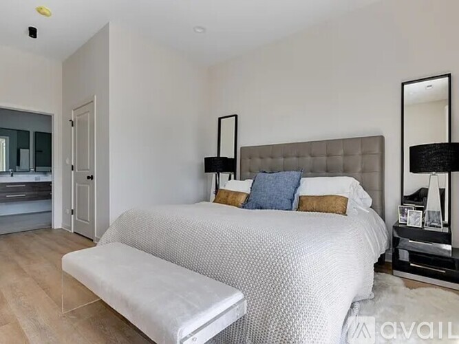 A bedroom with a large bed and a bench in front of it.