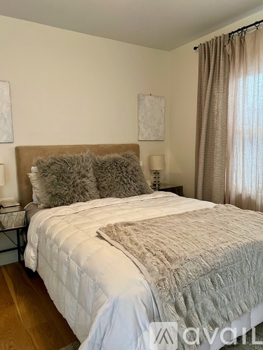 A bed with a white comforter and a grey pillow is in the image.