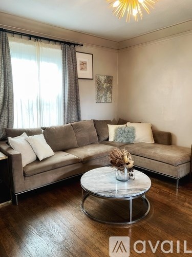 A living room with a brown sofa and a round marble coffee table.
