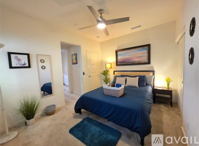 A bedroom with a blue bed and a ceiling fan.