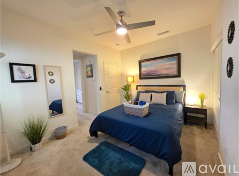 A bedroom with a blue bed and a ceiling fan.