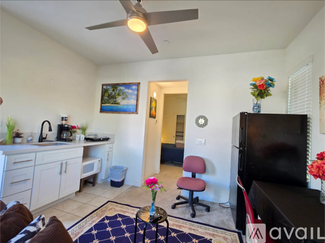 A living room with a ceiling fan and a painting on the wall.