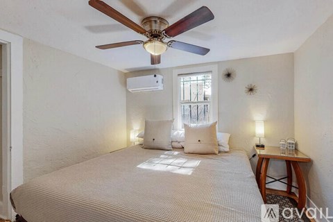 A bedroom with a bed, a ceiling fan, and a window.