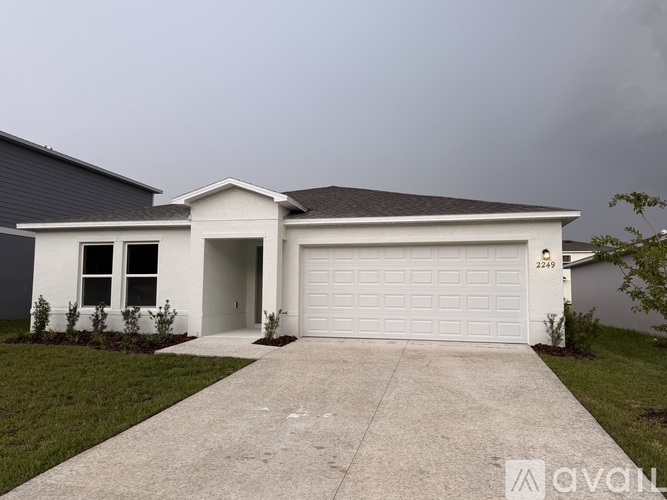 A white house with a blue door and garage door is available for sale.