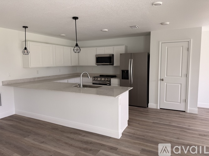 A kitchen with white cabinets and a stainless steel refrigerator.