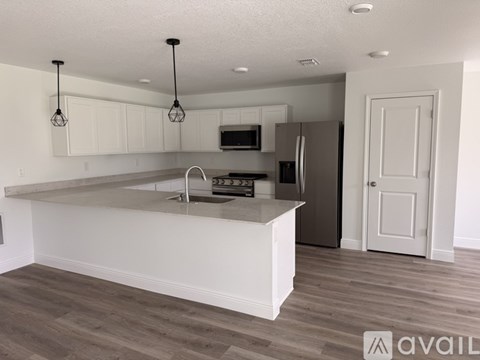 A kitchen with white cabinets and a stainless steel refrigerator.