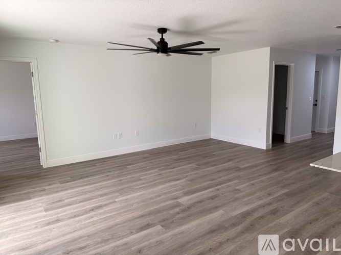 A spacious kitchen with wooden flooring and white walls.