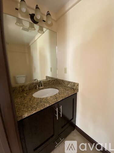 A bathroom with a granite countertop and a sink.