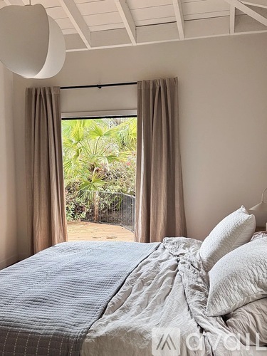 A bedroom with a bed and a window overlooking a garden.