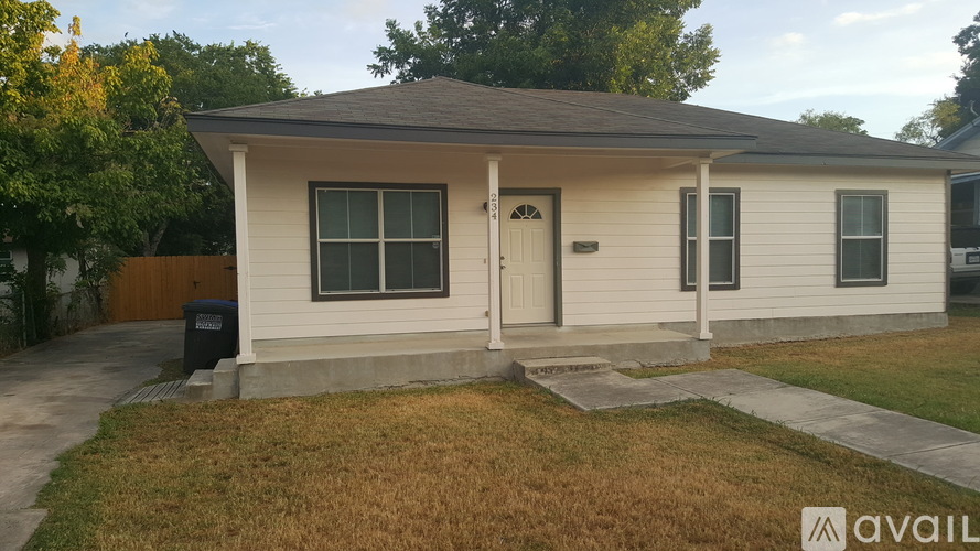 A small house with a front yard and a trash can.