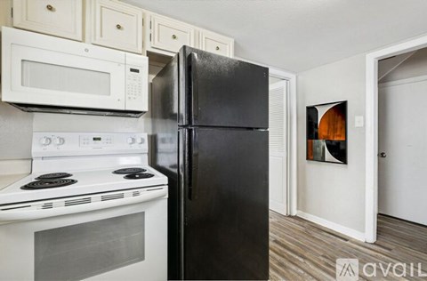 A black refrigerator is in a kitchen with a white stove and microwave.