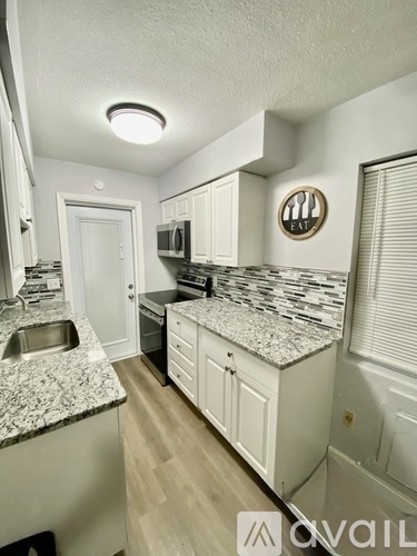 A kitchen with granite countertops and white cabinets.