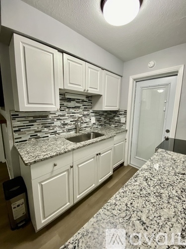 A kitchen with white cabinets and a granite countertop.