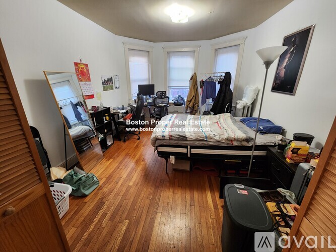 A bedroom with a bed, desk, and cluttered space.