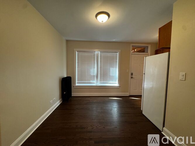 A room with a wooden floor and a window with blinds.