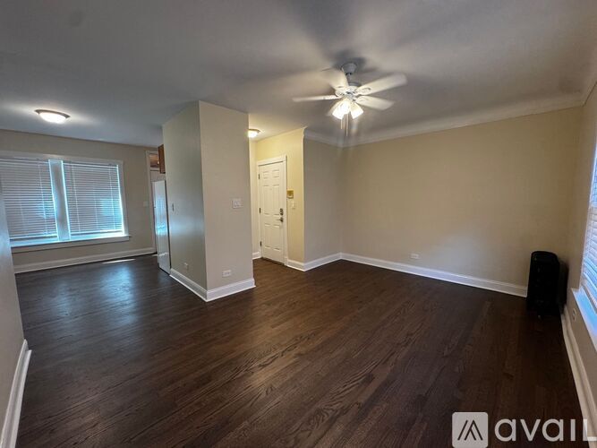 A spacious room with wood flooring and a ceiling fan.