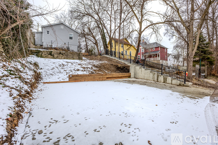 A snow-covered ground with a house and a yellow building in the background.