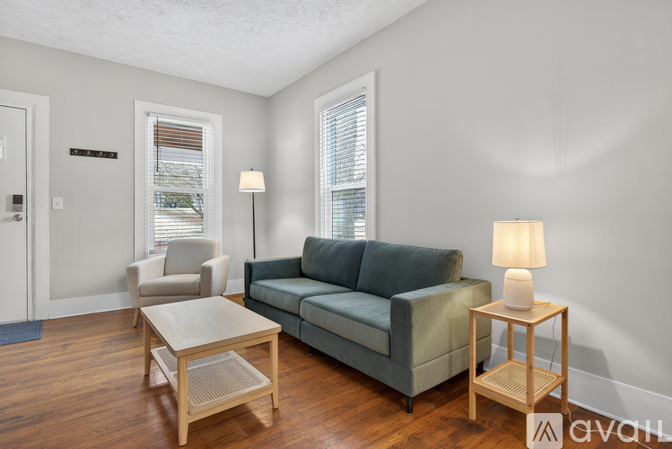 A living room with a grey couch, a wooden table, and a lamp.