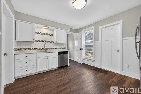 A kitchen with white cabinets and a wooden floor.