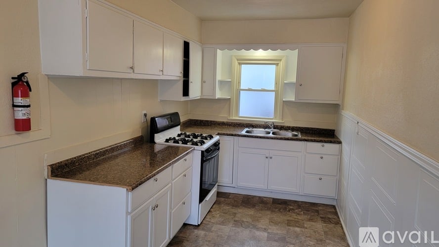 A kitchen with white cabinets and a brown countertop.