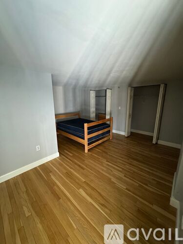 A bedroom with a bed and wooden floors.