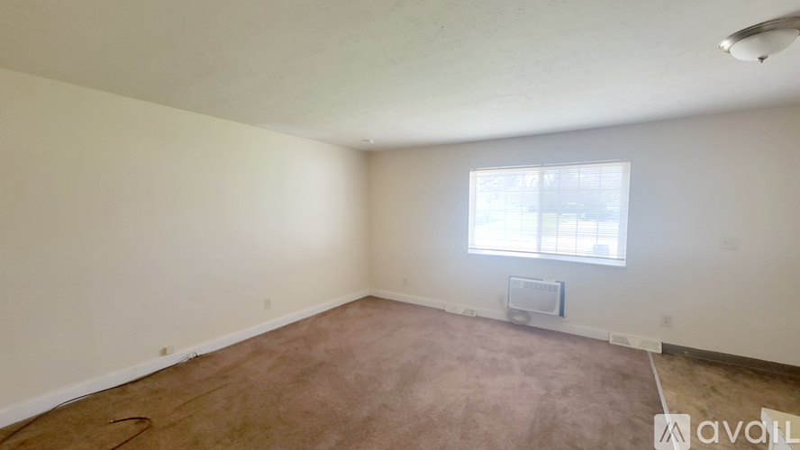 A room with a window and a carpeted floor.