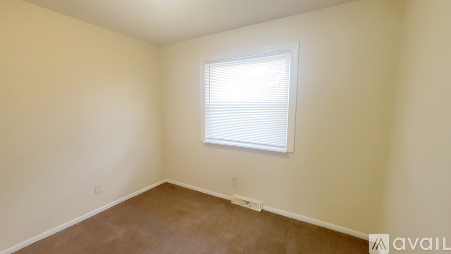 A room with a window and a carpeted floor.