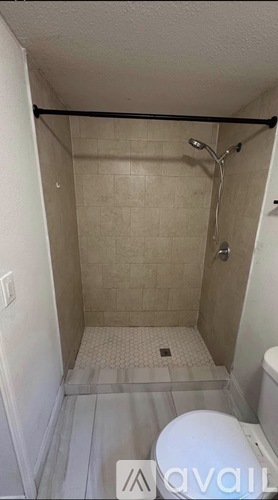 A small, white toilet is in a small bathroom with a walk-in shower.