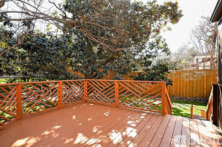 A wooden deck with a railing and trees in the background.