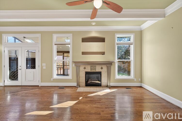 A living room with a fireplace and a fan on the ceiling.