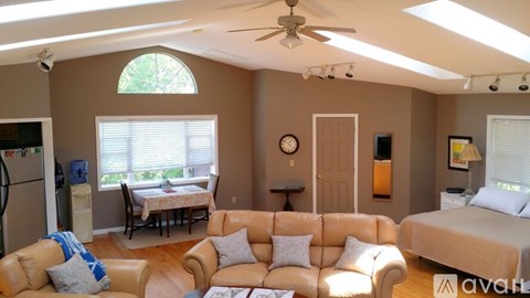 A living room with a tan couch and a ceiling fan.