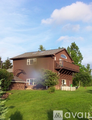 A brown house with a balcony and a hot tub in the backyard.