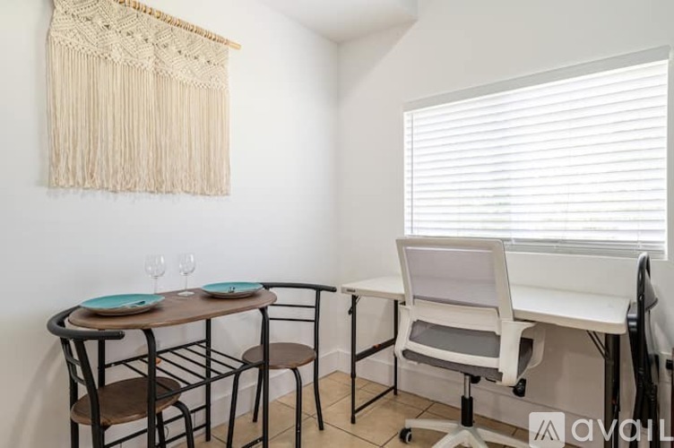 A room with a table, chairs, and a window with blinds.