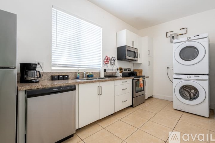 A kitchen with white cabinets and appliances, a microwave, and a washing machine.