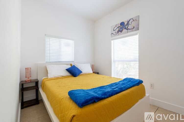 A bedroom with a yellow bedspread and a blue throw on the bed.