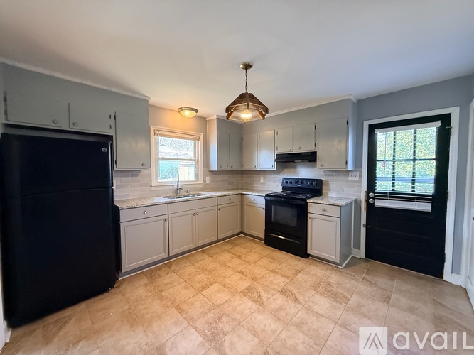 A kitchen with black appliances and a tiled floor.