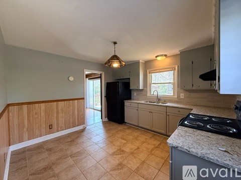 A kitchen with a black refrigerator and a stove top oven.