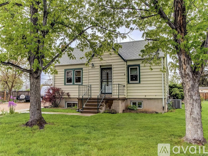 A house with a green lawn and trees in front.