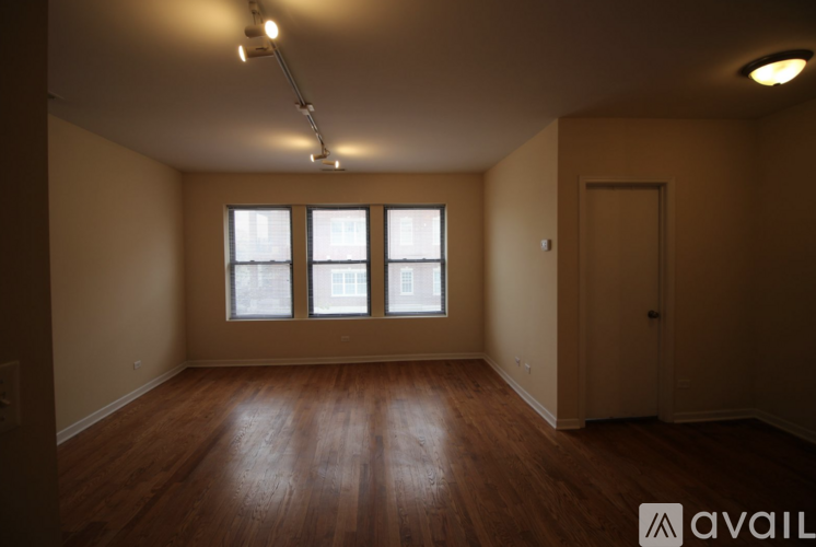 A room with wooden floors and a window with a view of buildings outside.