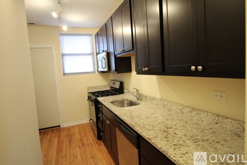 A kitchen with black cabinets and a granite countertop.